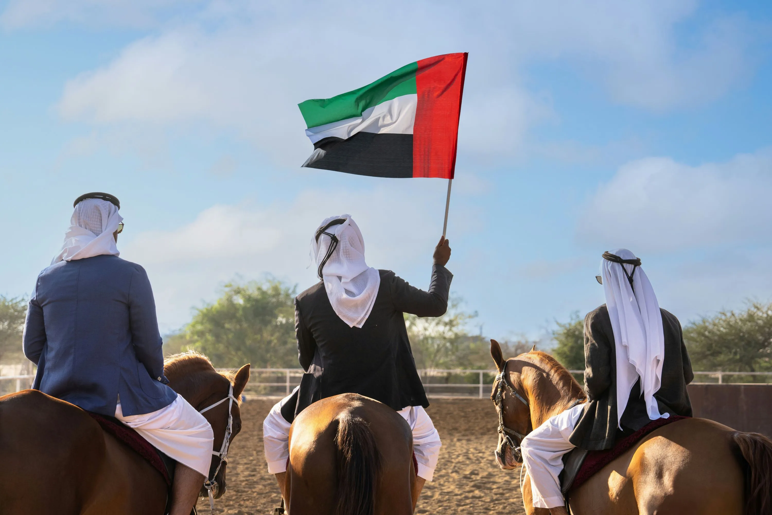 Drei Männer auf Pferden mit Emirate Flagge